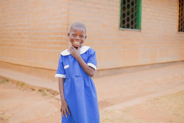 Student Alinafe stands and smiles outside her classroom