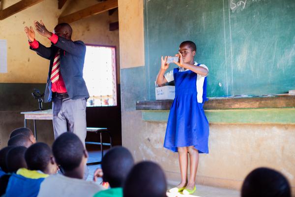 Peter and a student stand in front of class using the flashcards