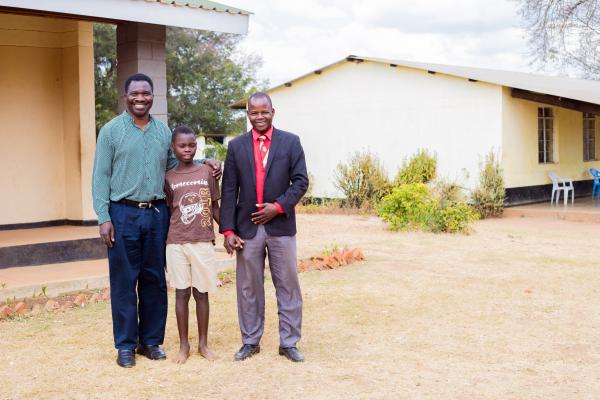 Theonas, Peter and Mphatso stand in front of the learning centre