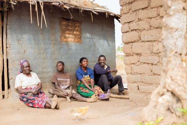 Mphatso sits with his family outside their home