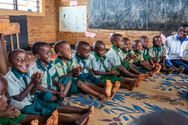 Teacher Olivier sits with his students in class