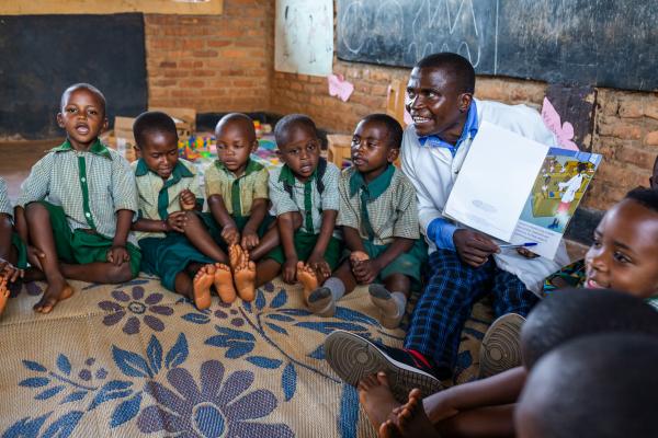 Teacher Olivier and his students sat on the floor with a storybook.