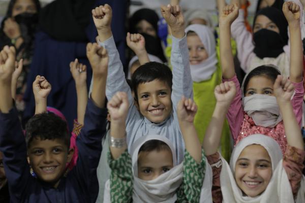 Children in the classroom smiling with their hands up