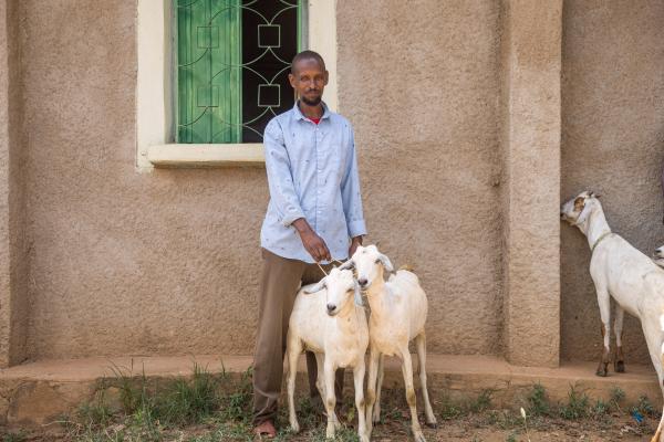 A farmer holding two goats.