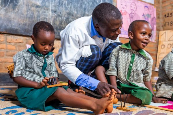 Primary school student Joshua and his friend in class with teacher Olivier.
