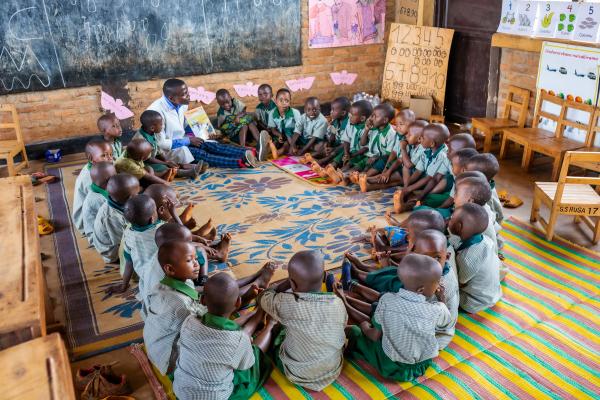 Primary school students and teacher Olivier sat in a circle in a classroom during a lesson.