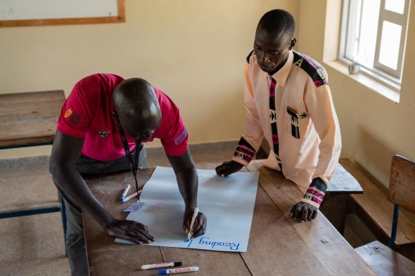 Volunteer Alfred works with teacher Elijah to create some teaching materials