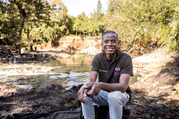 Lawrence, VSO community volunteer by polluted river in Nairobi