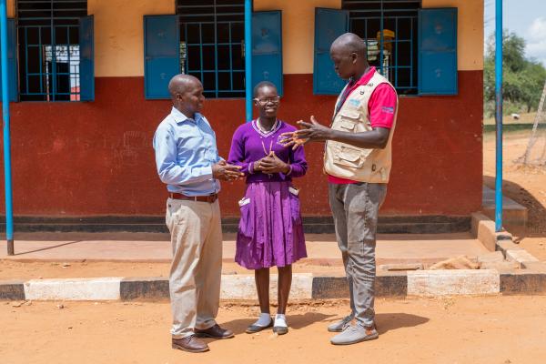 Teacher Stanley, Alice and Vvolunteer Alfred stand in her school