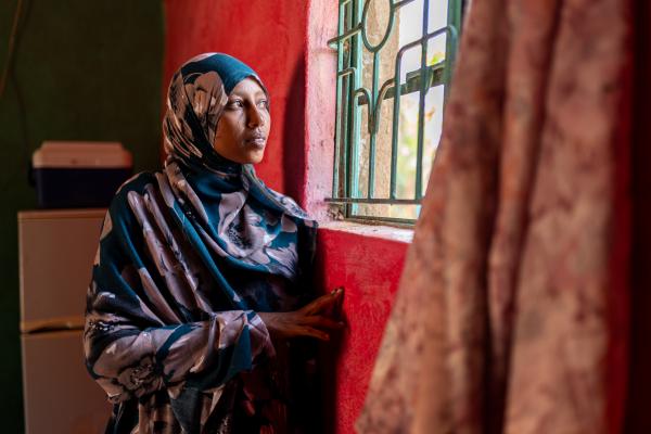 Safia looking out from the window in her house