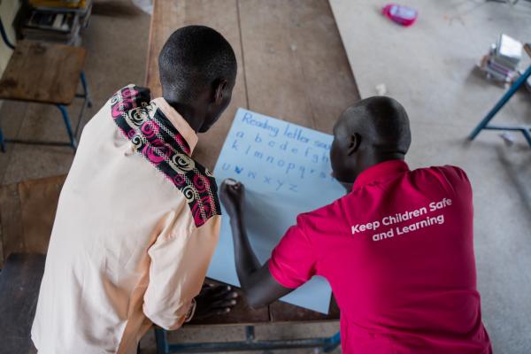 Teacher Elijah and VSO volunteer Alfred working together to create teaching materials