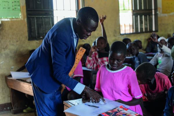 Teacher Denis helping Nangiro with her work in class.