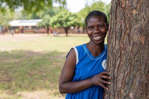 Student Juliet, smiling at the camera, stood next to a tree.