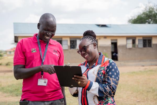 VSO volunteer Alfred (left) in the school playground with VSO staff member (Oliver). 
