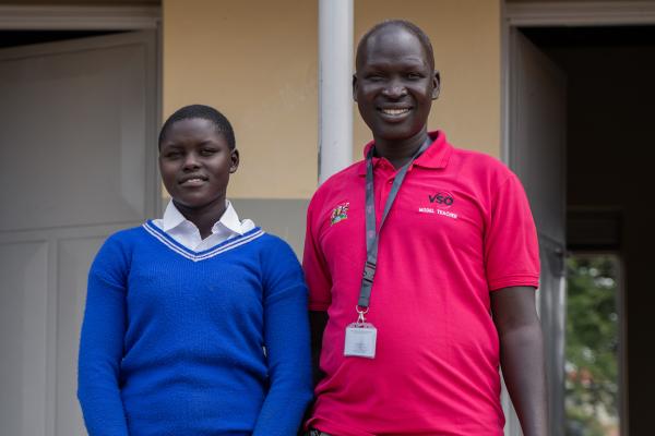Student Emily and VSO volunteer Alfred, smiling at the camera.