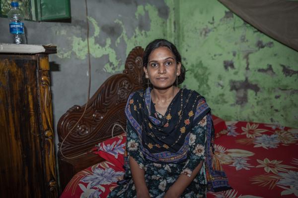 Rokeya sat on a bed.