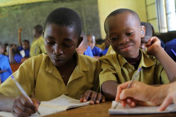 Two boys sit and work at their desk in a busy classroom in their school for children with disabilities in Nyamasheke, Rwanda