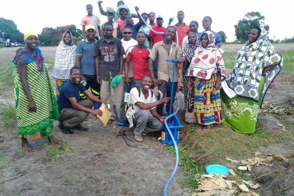 VSO Chris Takyuka teaching farmers how to use a manual water pump for irrigation