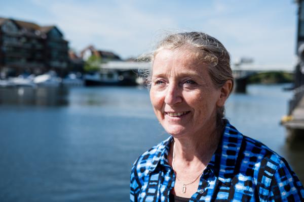Clare Hawkes, a VSO volunteer Woman standing outside next to a river looking out to the water