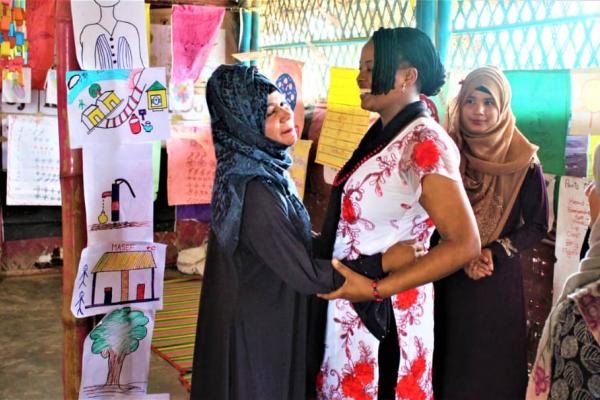 VSO volunteer Ann Wambui with rohingya mother Shofika, smiling and happy.