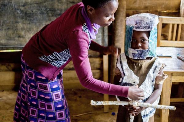 Teacher Josephine with child in moto costume made of rice sacks Teacher with child in moto costume made of rice sacks