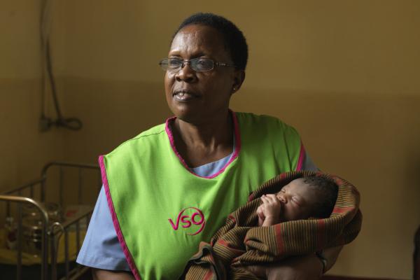 A VSO midwife holding a baby 