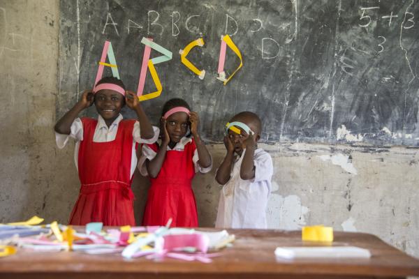 Isabella's students learn about letter forms Children stand by the blackboard in a Kenyan classroom