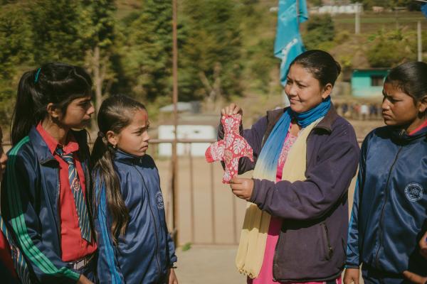 A VSO trained Big Sister shows girls how to make a sanitary pad