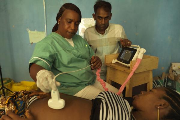 Midwife Catherine Swaray scans 17-year-old Mariama Jalloh, assisted by VSO volunteer Dr Kiran Cheedella