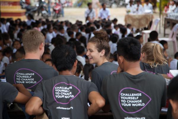 ICS volunteers sit in front of a big group of children in Cambodia