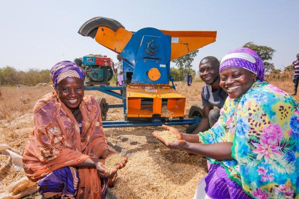 Threshing machine with two IMA4P farmers, Fatima Zubairu and Fatima Al Hassan, with volunteer Musa in Mokwa, Niger State, Nigeria.