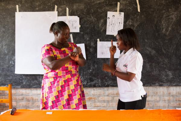 Brown Niyonsaba teaching sign language to community health worker Judith Mugirente 