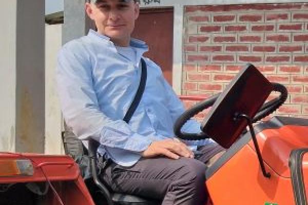 a man sat on a tractor outside, looking at the camera