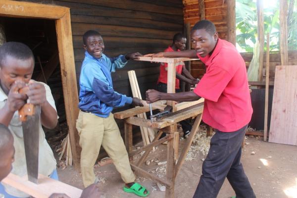 a group of rwandan men making furniture outside